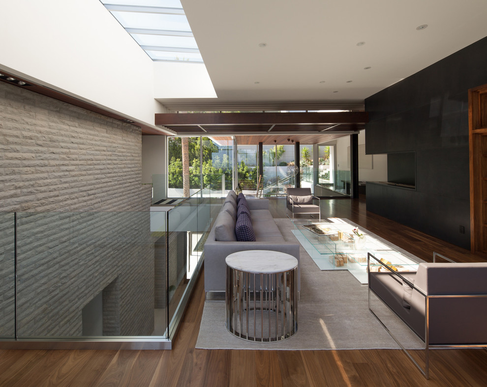 Modelo de salón abierto minimalista grande con paredes grises y suelo de madera clara