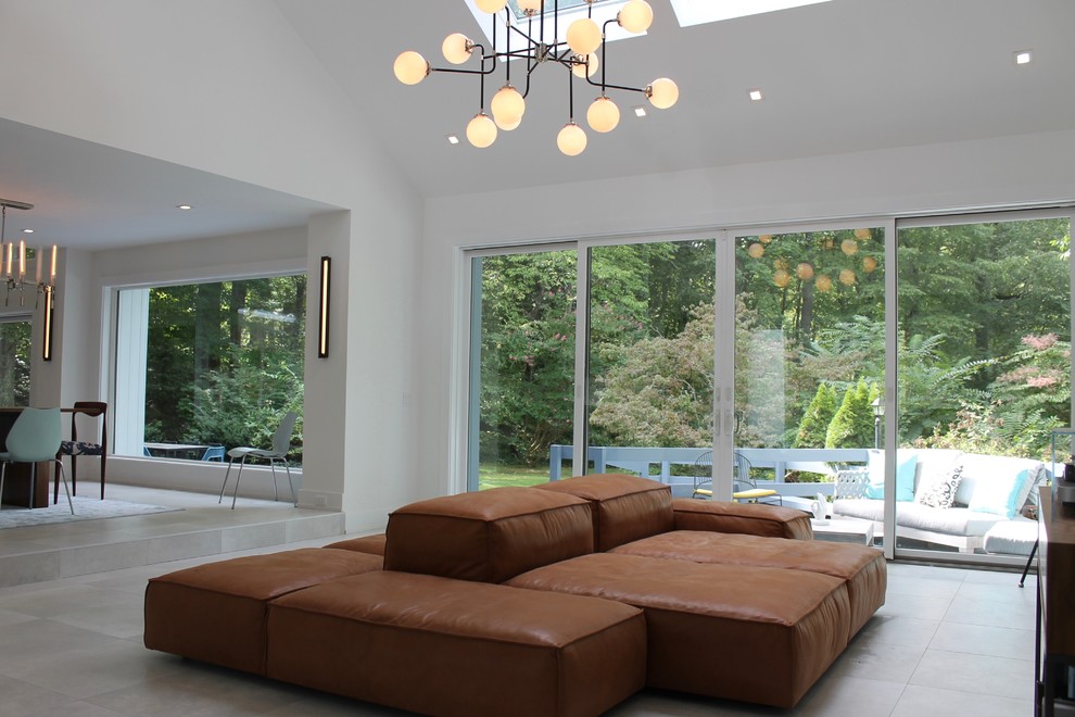 На фото: огромная гостиная комната в стиле модернизм с белыми стенами, полом из керамогранита и стандартным камином с