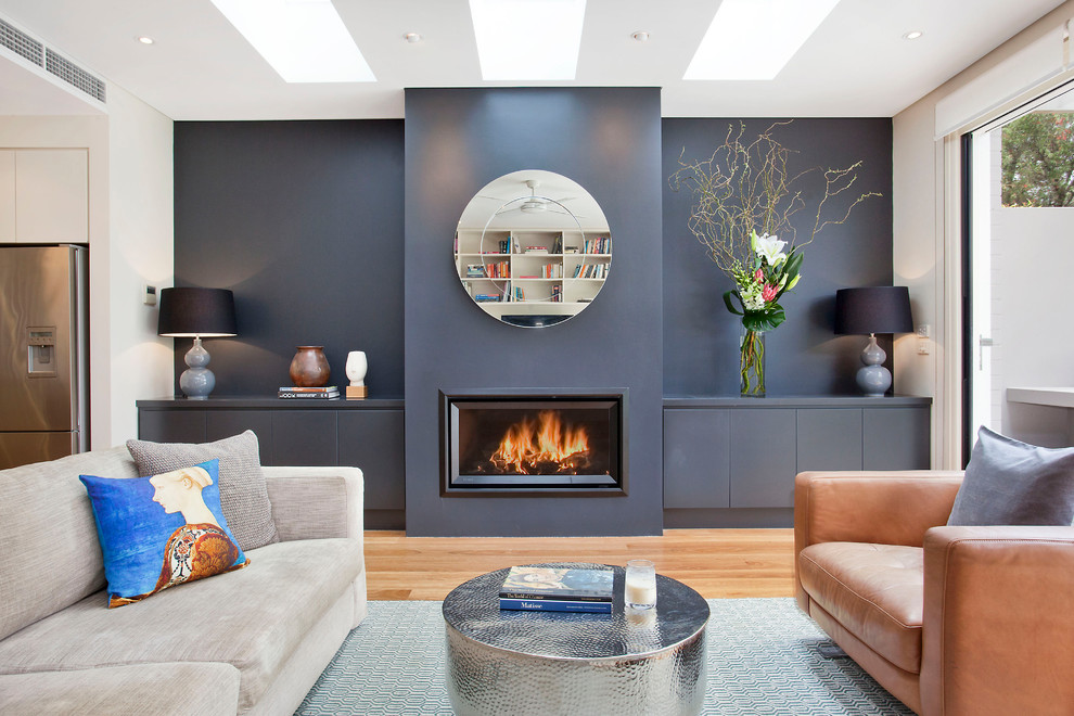 シドニーにあるコンテンポラリースタイルのおしゃれなLDK (青い壁、無垢フローリング、茶色い床、横長型暖炉、テレビなし) の写真