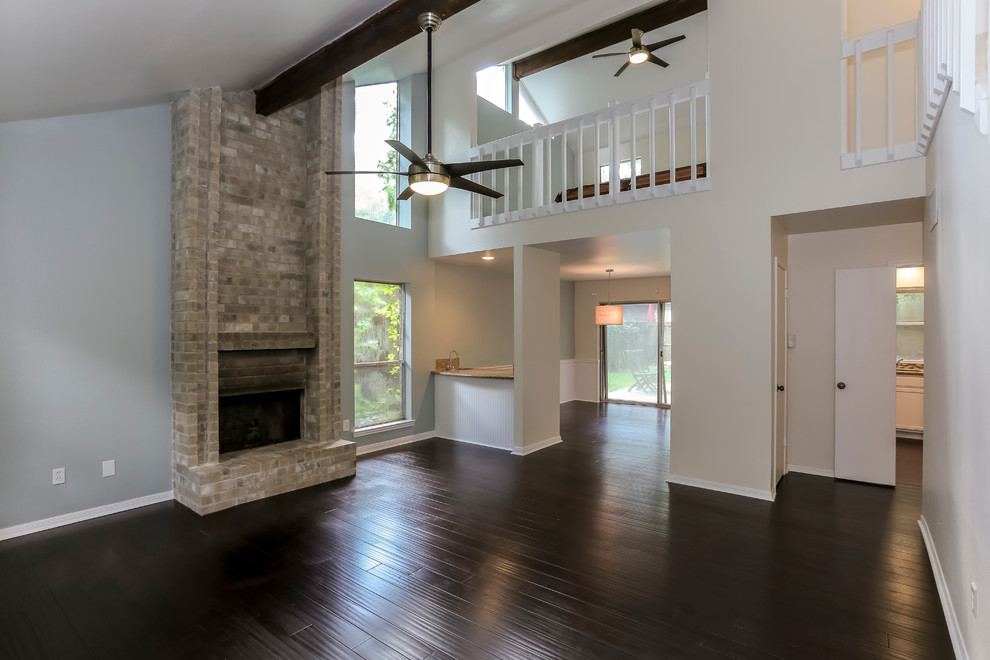 Example of a large classic open concept dark wood floor and brown floor living room design in Houston with gray walls, a standard fireplace, a stone fireplace and no tv