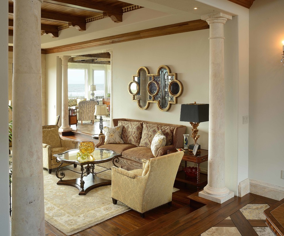 Cette image montre un grand salon méditerranéen ouvert avec un mur beige, parquet foncé, une cheminée standard et un manteau de cheminée en pierre.