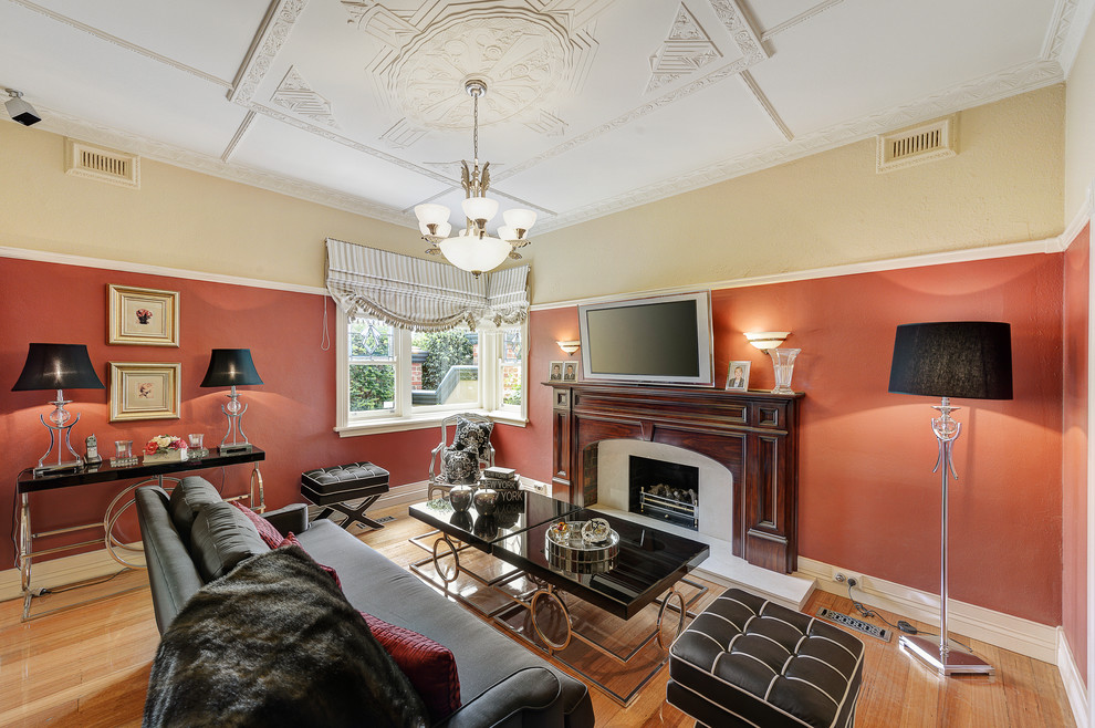 Example of a large classic formal and open concept medium tone wood floor living room design in Melbourne with red walls, a standard fireplace, a wood fireplace surround and a wall-mounted tv