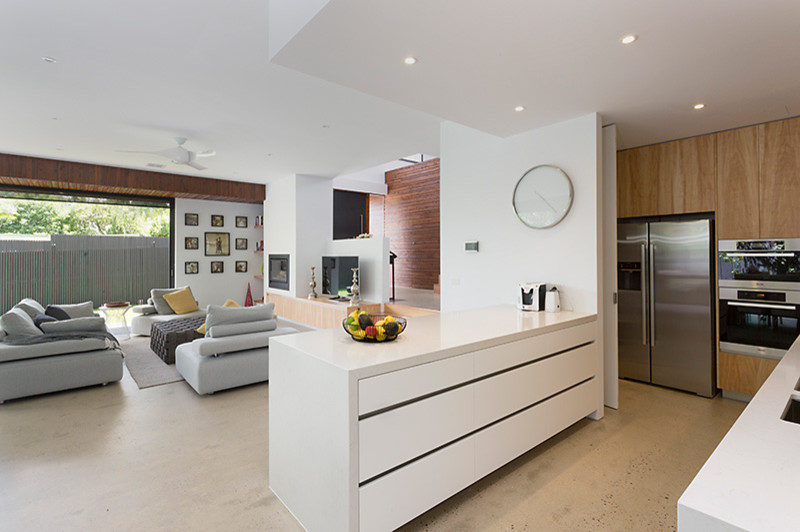 Aménagement d'un grand salon contemporain ouvert avec un mur blanc, sol en béton ciré, une cheminée standard, un manteau de cheminée en plâtre, un téléviseur indépendant et un sol gris.