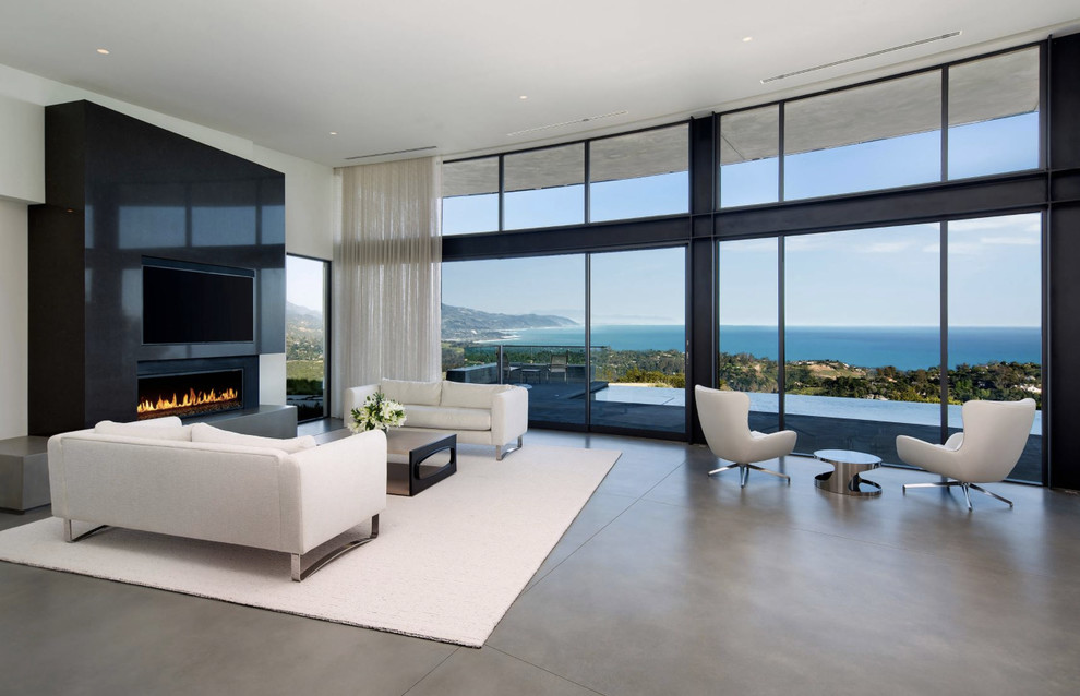 Стильный дизайн: гостиная комната в современном стиле с белыми стенами, бетонным полом, горизонтальным камином, телевизором на стене и серым полом - последний тренд