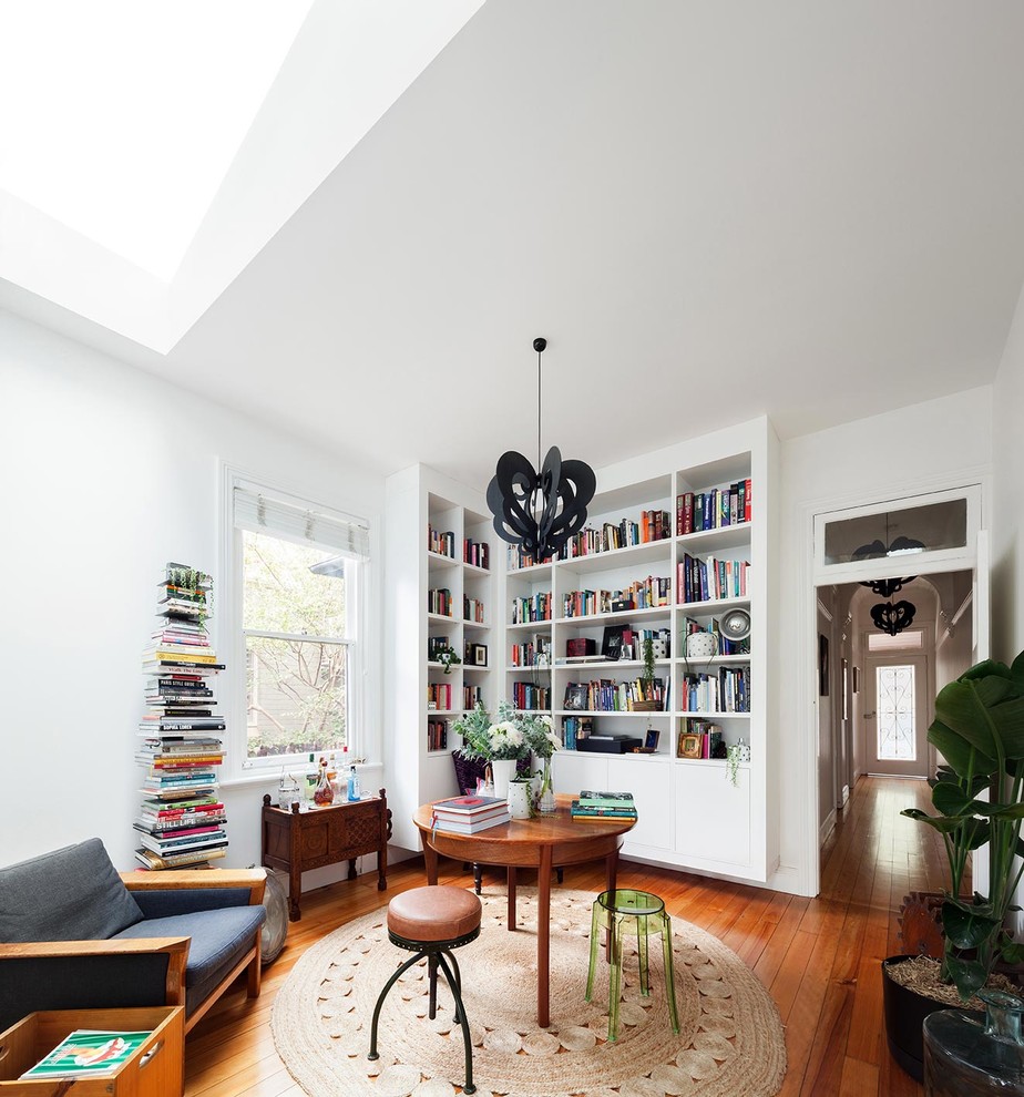 Ispirazione per un soggiorno moderno di medie dimensioni e chiuso con pareti bianche, pavimento in legno massello medio e libreria