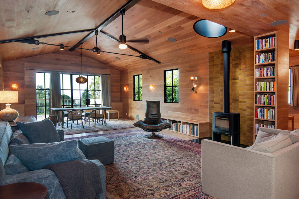 Ejemplo de salón abierto actual con paredes marrones, suelo de madera en tonos medios, estufa de leña y suelo marrón