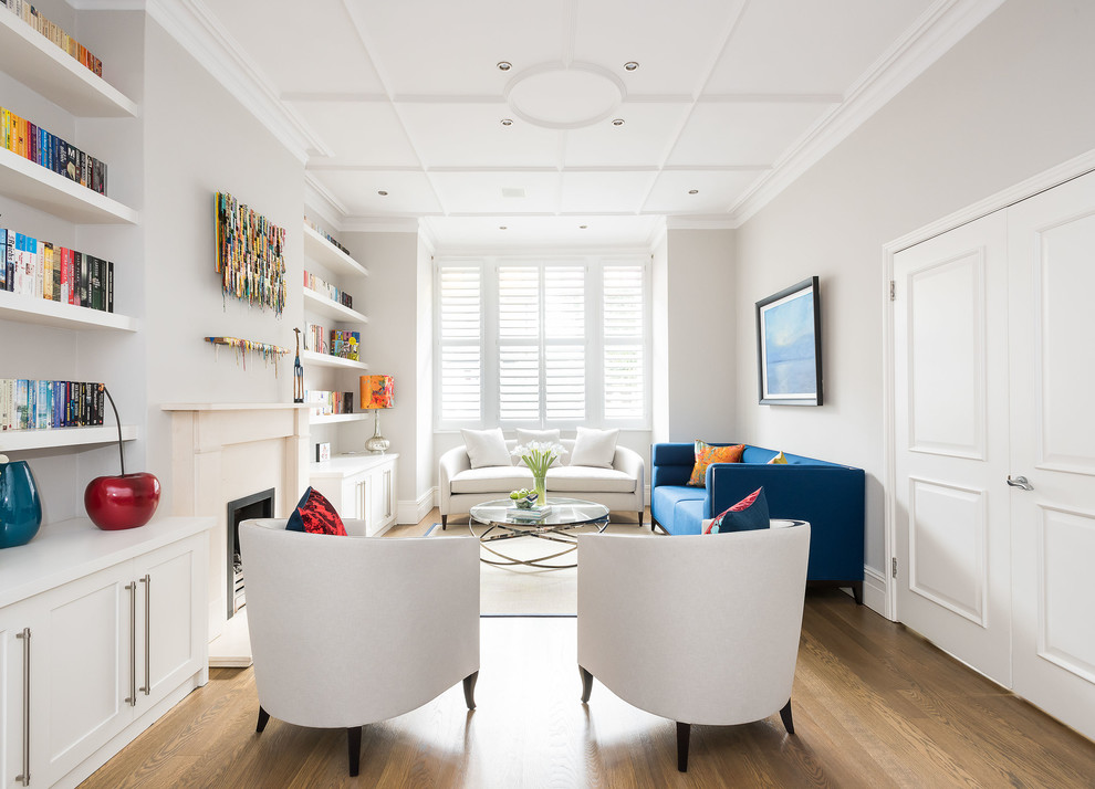 Foto di un soggiorno chic di medie dimensioni con libreria, pareti beige, parquet chiaro, camino classico e pavimento marrone
