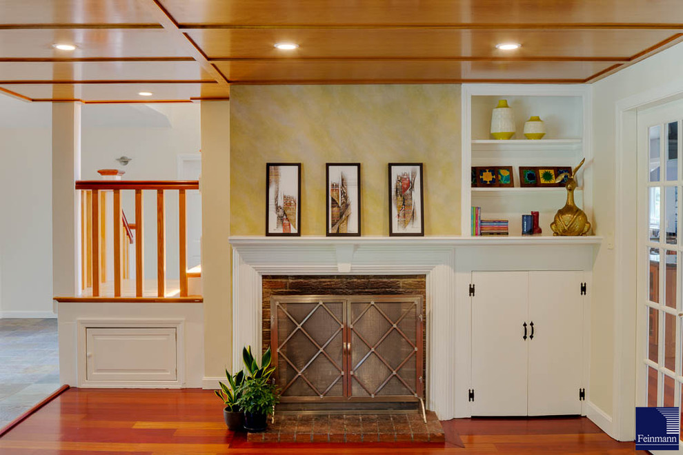 На фото: гостиная комната среднего размера в стиле неоклассика (современная классика) с паркетным полом среднего тона, стандартным камином, фасадом камина из кирпича и желтыми стенами