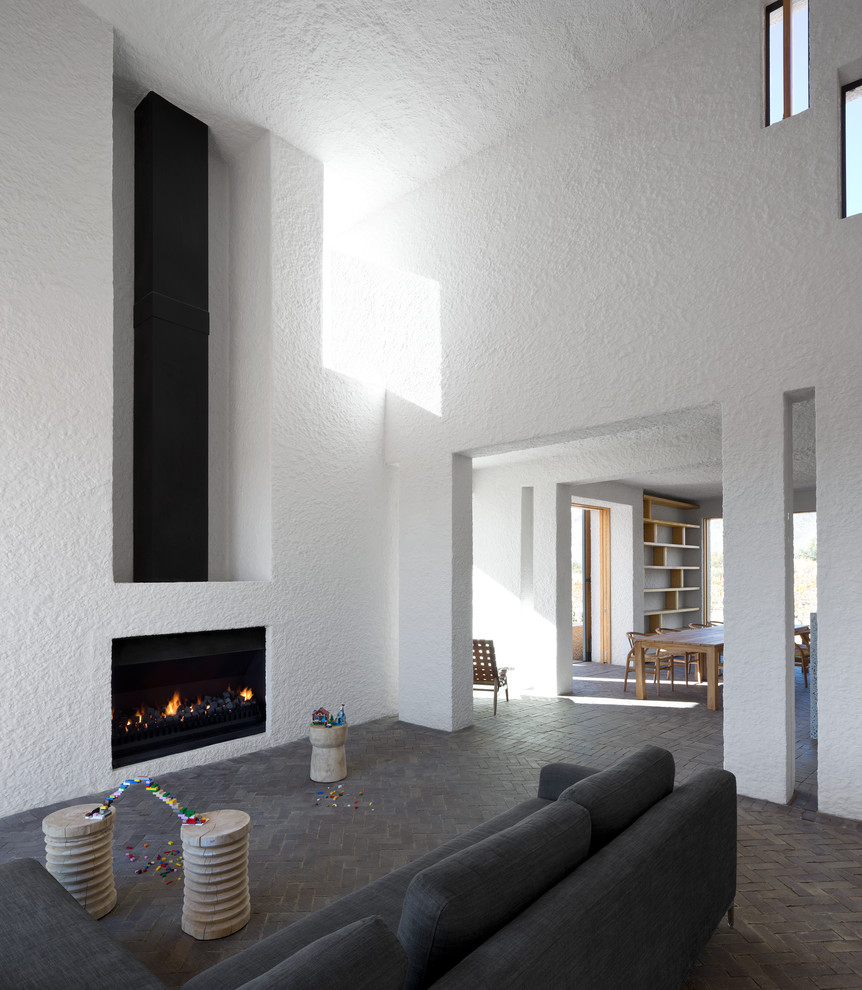 Repräsentatives Modernes Wohnzimmer mit weißer Wandfarbe, Backsteinboden, Kamin und verputzter Kaminumrandung in Sonstige