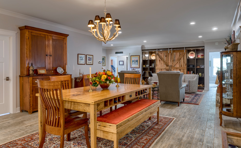 This is an example of a large classic dining room in Other with grey walls, ceramic flooring, a wood burning stove, a stone fireplace surround and grey floors.