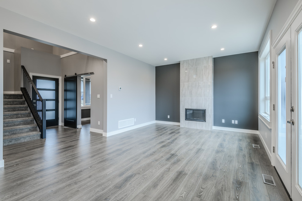 Aménagement d'un salon moderne de taille moyenne et ouvert avec une salle de réception, un mur gris, sol en stratifié, une cheminée standard, un manteau de cheminée en carrelage et un sol gris.