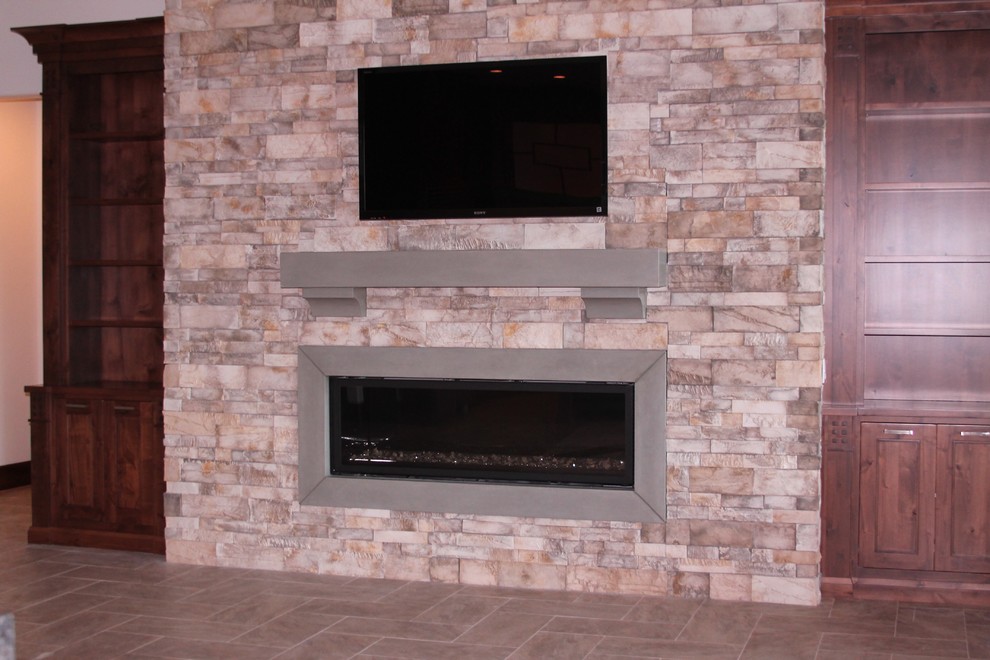 Foto di un soggiorno minimalista aperto con cornice del camino in pietra e TV a parete