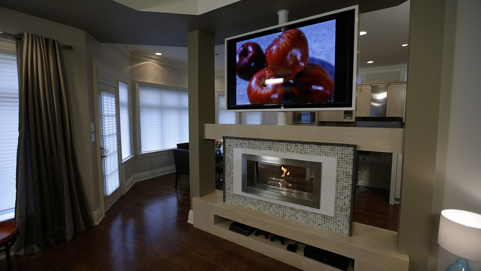 Photo of a medium sized contemporary open plan living room in Toronto with beige walls, medium hardwood flooring, a two-sided fireplace, a tiled fireplace surround and a built-in media unit.