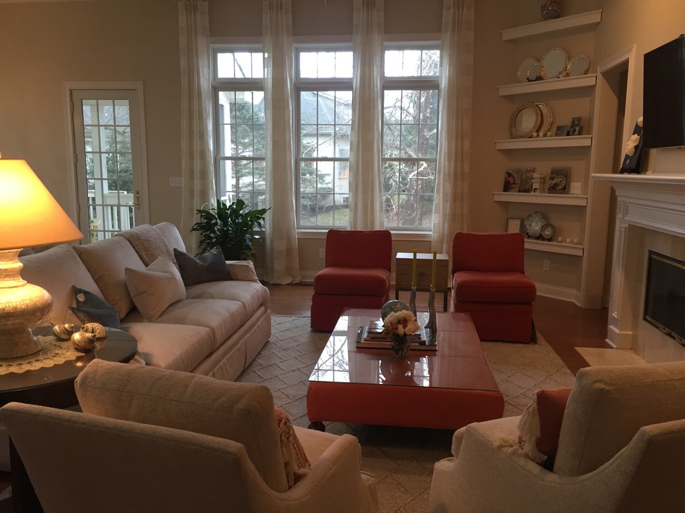 Immagine di un grande soggiorno classico aperto con pareti beige, pavimento in legno massello medio, camino classico, TV a parete e pavimento marrone