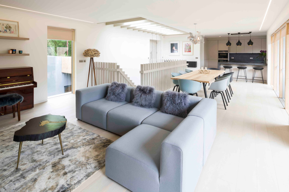 This is an example of a medium sized contemporary open plan living room in Cornwall with white walls, light hardwood flooring and beige floors.