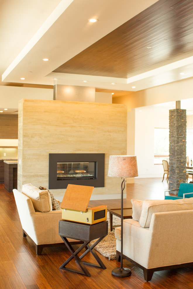На фото: большая открытая гостиная комната в современном стиле с бежевыми стенами, полом из бамбука, двусторонним камином, фасадом камина из штукатурки и телевизором на стене с