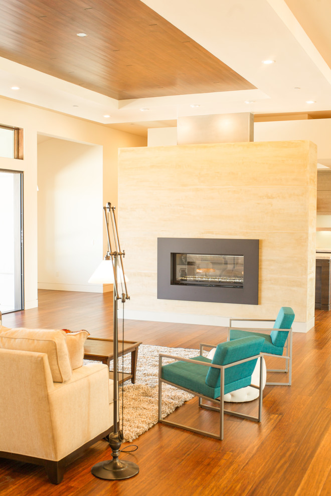 Aménagement d'un grand salon contemporain ouvert avec un mur beige, parquet en bambou, une cheminée double-face, un manteau de cheminée en plâtre et un téléviseur fixé au mur.