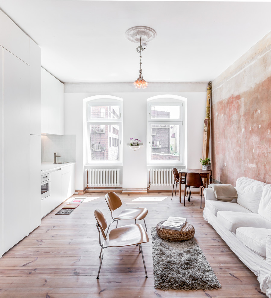 Repräsentatives, Offenes, Kleines Modernes Wohnzimmer ohne Kamin mit weißer Wandfarbe und braunem Holzboden in Berlin