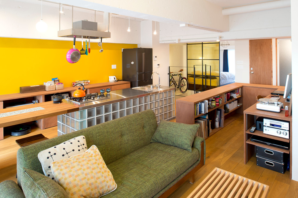 На фото: открытая гостиная комната в современном стиле с желтыми стенами и паркетным полом среднего тона с