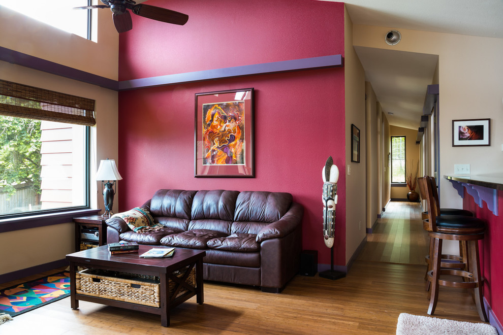 Cette photo montre un salon tendance ouvert avec un mur rouge et un sol en bois brun.