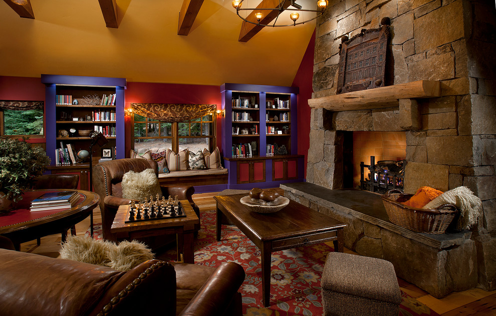 This is an example of a rustic living room in Sacramento with red walls, medium hardwood flooring, a standard fireplace and a stone fireplace surround.