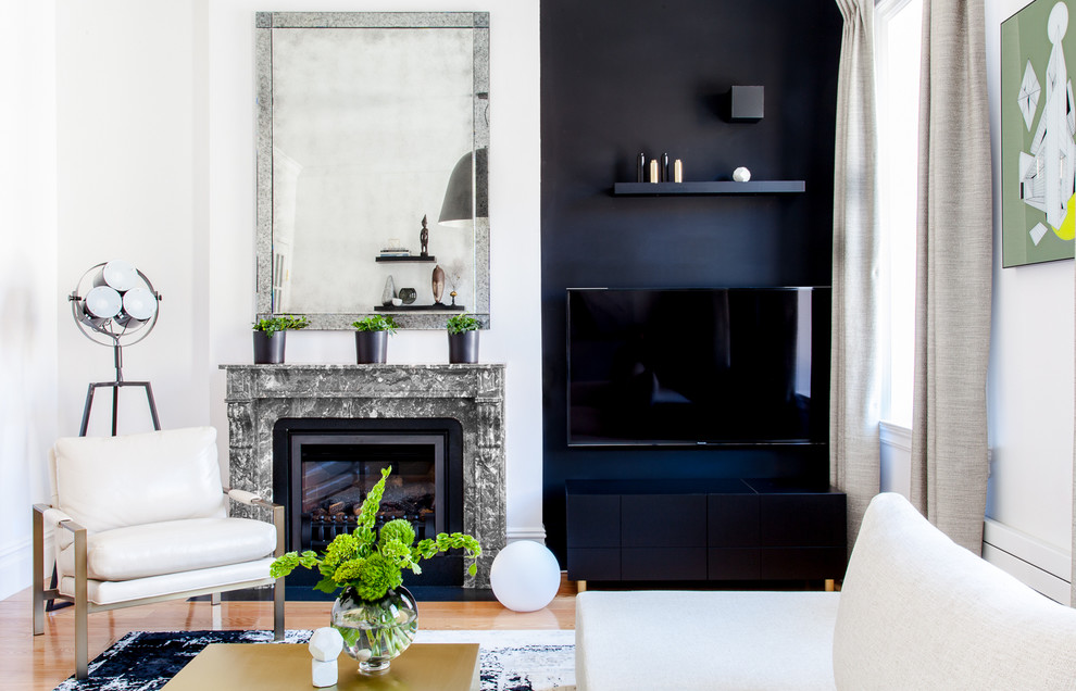 Стильный дизайн: большая парадная, изолированная гостиная комната в стиле модернизм с черными стенами, паркетным полом среднего тона, стандартным камином, фасадом камина из камня и телевизором на стене - последний тренд