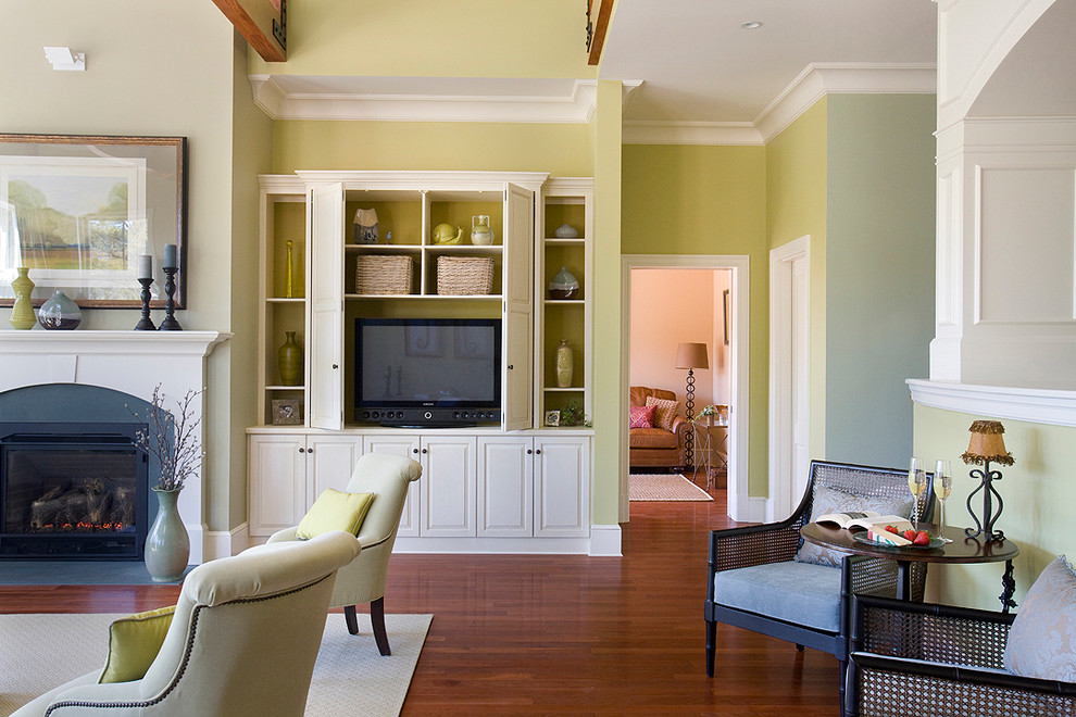 На фото: большая открытая гостиная комната:: освещение в классическом стиле с зелеными стенами, стандартным камином, скрытым телевизором, паркетным полом среднего тона, фасадом камина из дерева и ковром на полу с