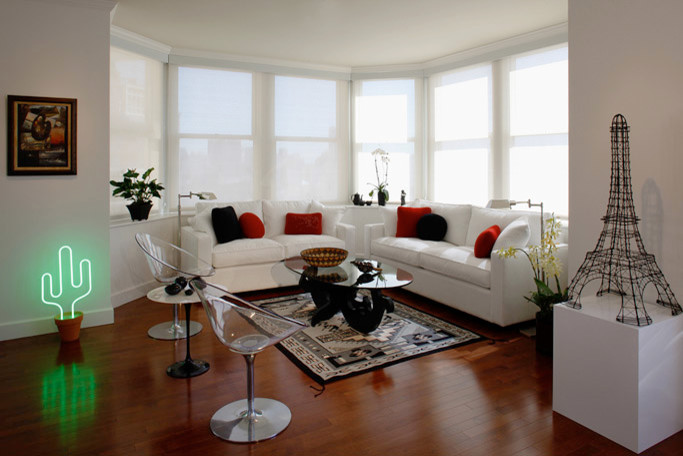 Cette image montre un petit salon bohème ouvert avec un mur blanc et un sol en bois brun.