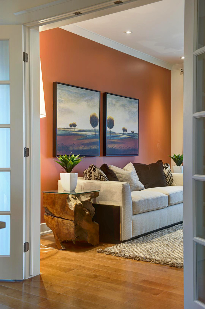 На фото: большая парадная, открытая гостиная комната в стиле неоклассика (современная классика) с оранжевыми стенами и светлым паркетным полом без камина, телевизора с