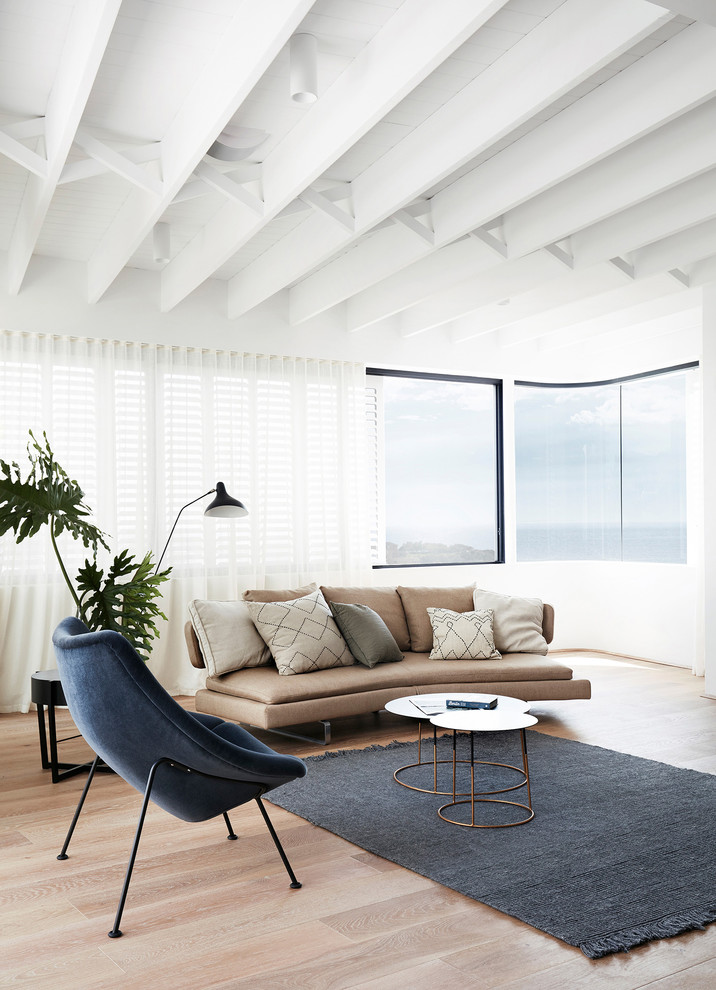Пример оригинального дизайна: открытая гостиная комната в современном стиле с белыми стенами, светлым паркетным полом и коричневым диваном