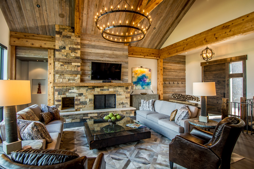 Example of a large mountain style open concept and formal medium tone wood floor living room design in Albuquerque with beige walls, a stone fireplace, a wall-mounted tv and a standard fireplace