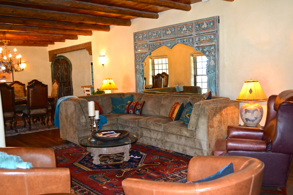 Modelo de salón abierto mediterráneo grande con paredes beige, suelo de madera oscura y televisor colgado en la pared