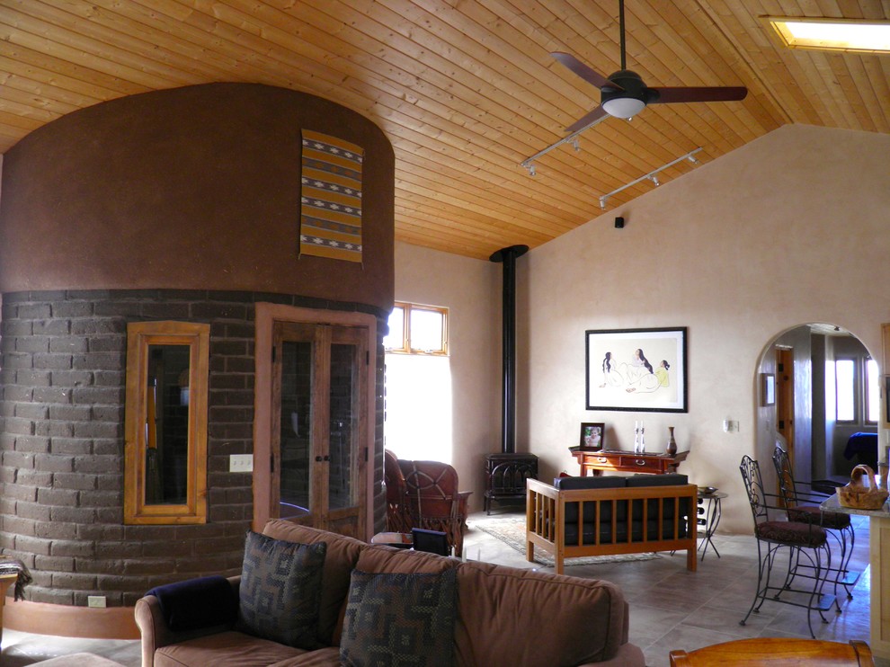 На фото: большая открытая гостиная комната в стиле фьюжн с бежевыми стенами, полом из травертина и печью-буржуйкой с
