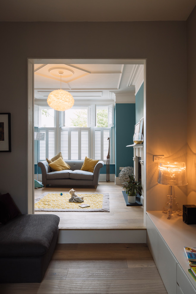 Источник вдохновения для домашнего уюта: гостиная комната среднего размера с синими стенами, светлым паркетным полом, стандартным камином, фасадом камина из дерева и коричневым полом
