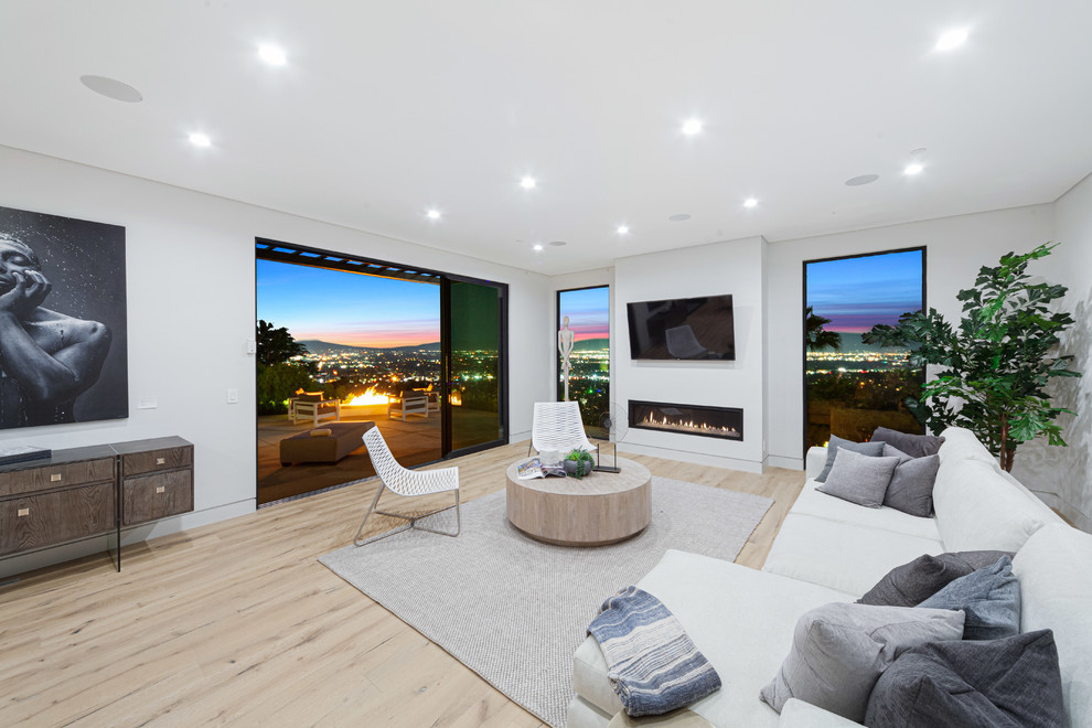 Großes, Offenes Modernes Wohnzimmer mit Kamin, TV-Wand, weißer Wandfarbe, hellem Holzboden und verputzter Kaminumrandung in Los Angeles