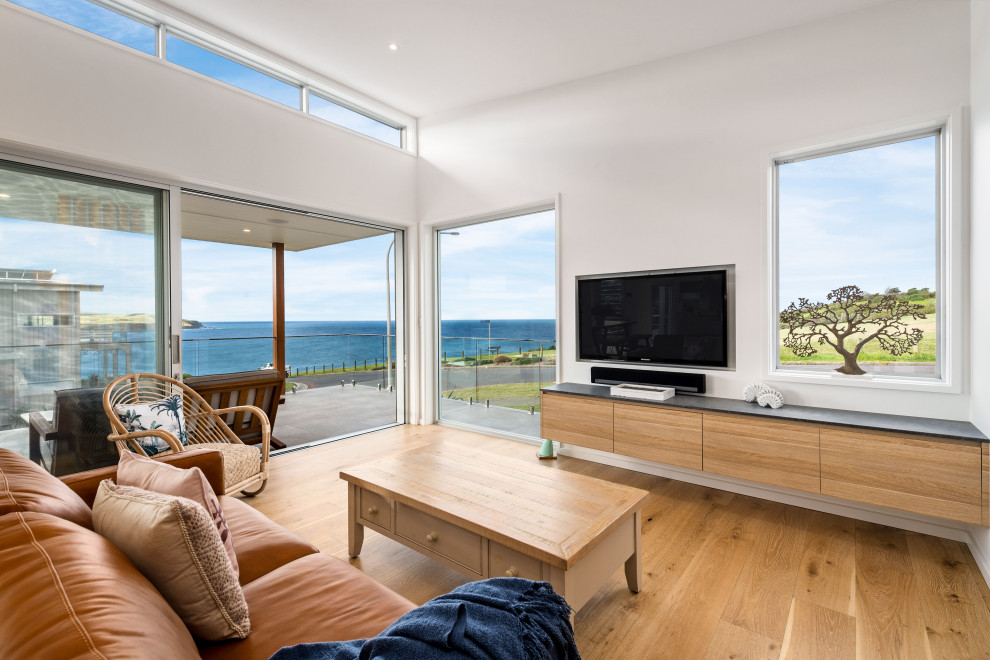 Großes, Offenes Maritimes Wohnzimmer mit weißer Wandfarbe, braunem Holzboden, TV-Wand und braunem Boden in Wollongong