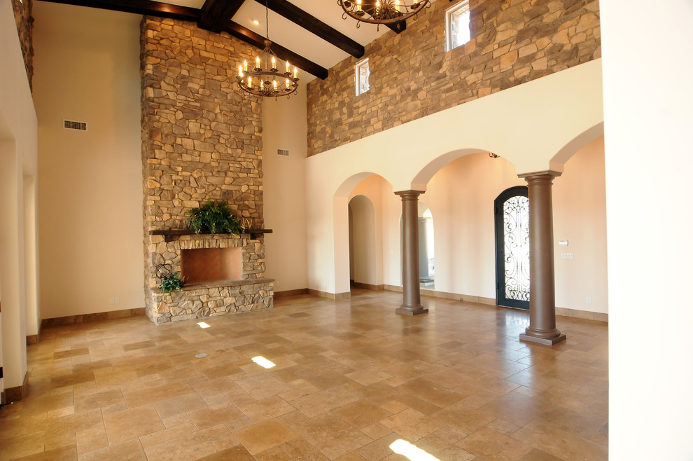 На фото: большая парадная, открытая гостиная комната в средиземноморском стиле с бежевыми стенами, полом из травертина, стандартным камином и фасадом камина из камня с
