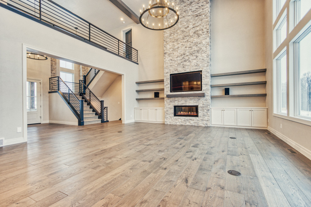 Großes, Repräsentatives Klassisches Wohnzimmer im Loft-Stil mit grauer Wandfarbe, braunem Holzboden, Kamin, Kaminumrandung aus Stein, Multimediawand und braunem Boden in Sonstige