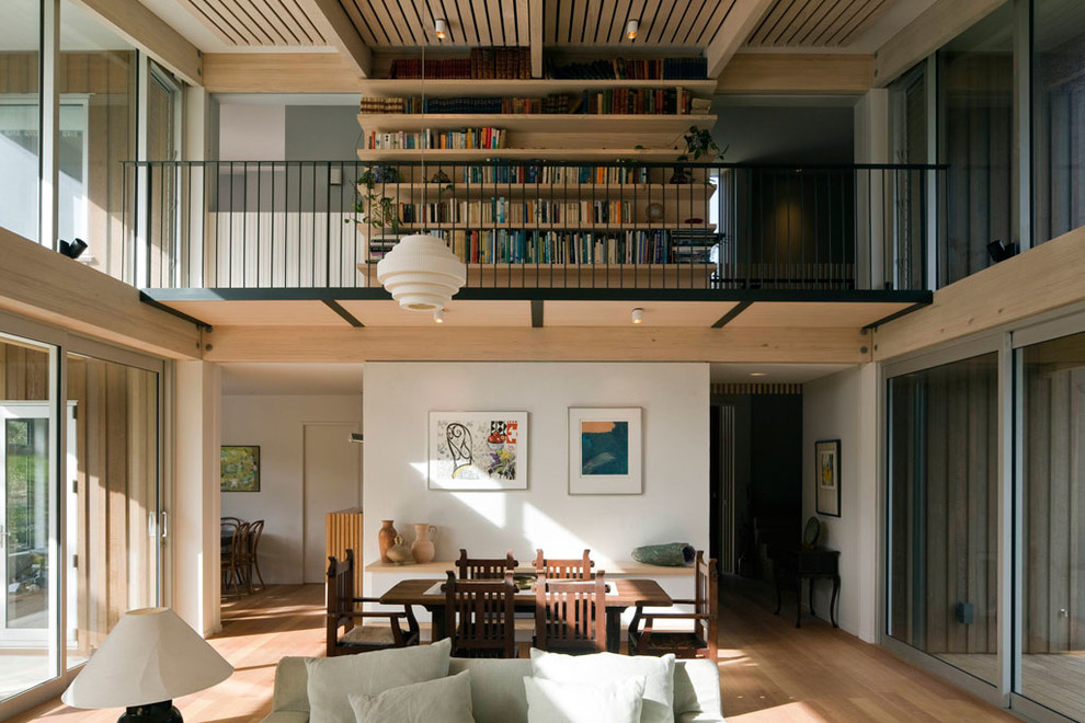 На фото: двухуровневая гостиная комната среднего размера в современном стиле с с книжными шкафами и полками, белыми стенами, светлым паркетным полом и деревянным потолком с