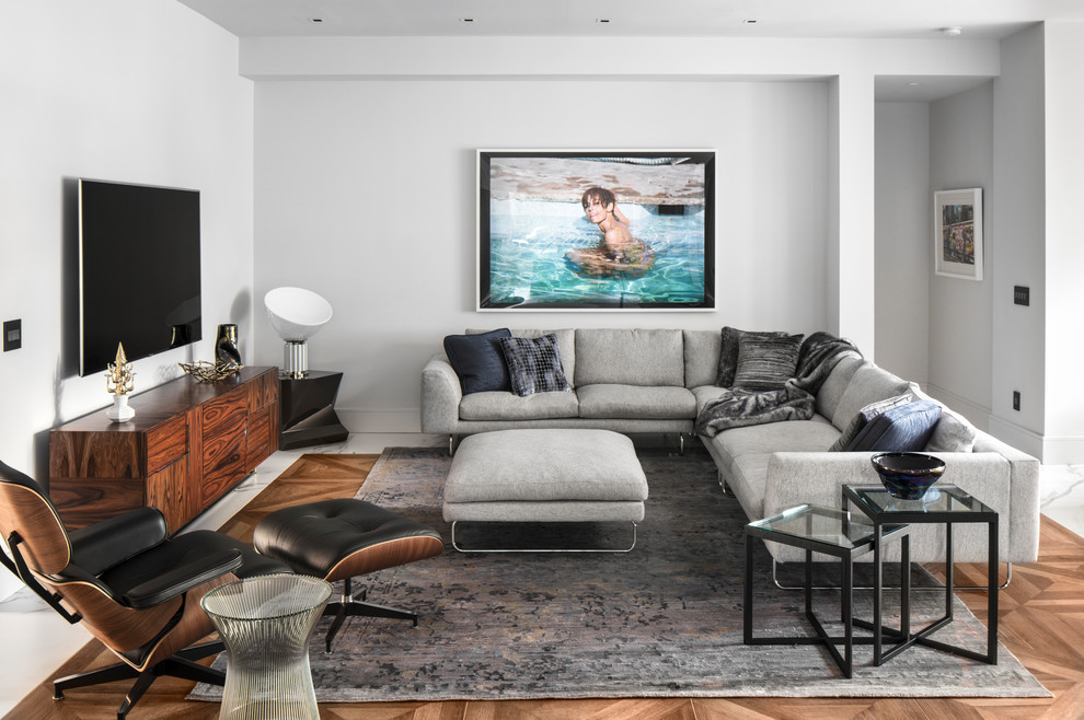 Источник вдохновения для домашнего уюта: гостиная комната в современном стиле с белыми стенами, паркетным полом среднего тона, телевизором на стене и коричневым полом