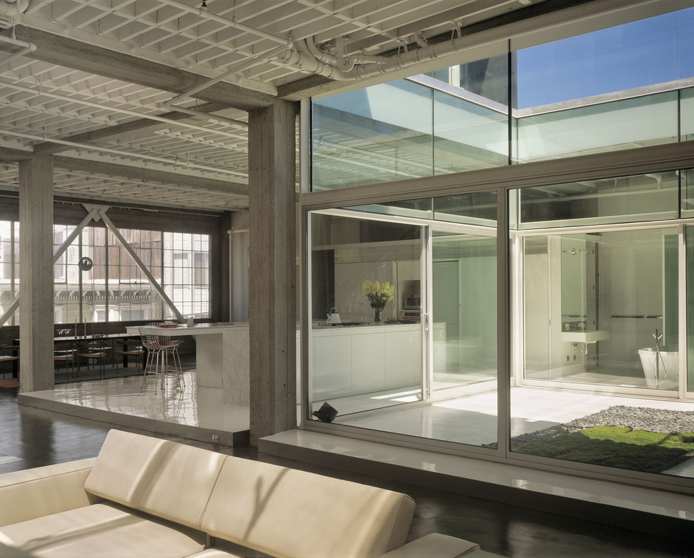 Imagen de salón abierto urbano de tamaño medio con paredes blancas, suelo de cemento y suelo gris