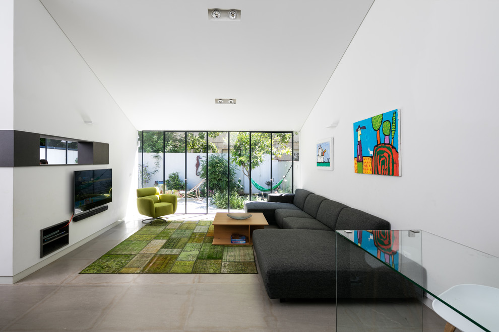 Imagen de salón para visitas abierto contemporáneo pequeño sin chimenea con paredes blancas, suelo de piedra caliza y televisor colgado en la pared
