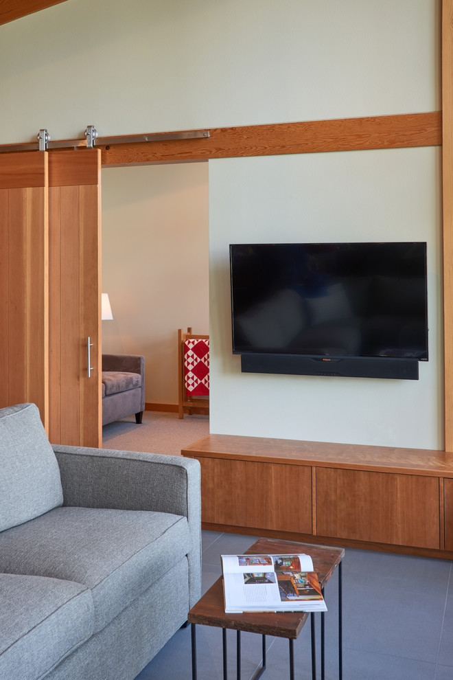 シアトルにある高級な中くらいなコンテンポラリースタイルのおしゃれなリビング (茶色い壁、コンクリートの床、薪ストーブ、金属の暖炉まわり、壁掛け型テレビ) の写真