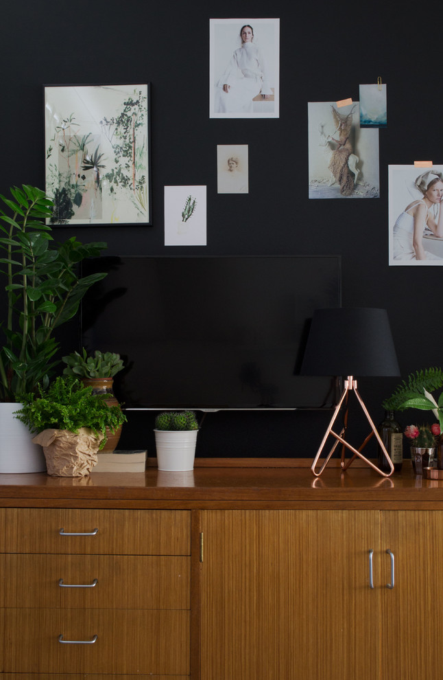Foto på ett mellanstort skandinaviskt allrum med öppen planlösning, med svarta väggar, heltäckningsmatta, en standard öppen spis, en spiselkrans i trä och en väggmonterad TV