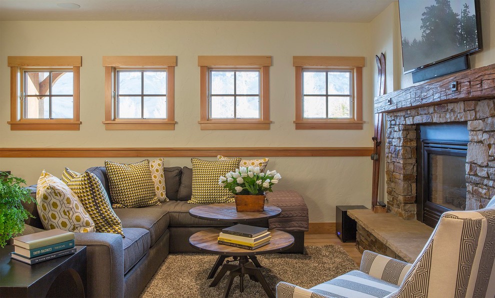 Offenes Uriges Wohnzimmer mit beiger Wandfarbe, hellem Holzboden, Kamin, Kaminumrandung aus Stein und TV-Wand in Houston