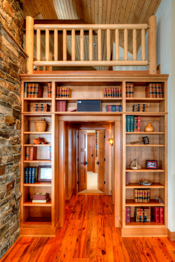 Foto di un soggiorno country di medie dimensioni e aperto con libreria, pavimento in legno massello medio, pareti beige, camino classico e pavimento marrone