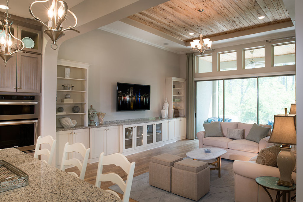 Esempio di un ampio soggiorno stile marino aperto con sala formale, pareti beige, parquet chiaro e TV a parete