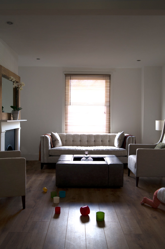 Immagine di un soggiorno moderno di medie dimensioni e chiuso con pareti bianche, parquet chiaro, camino classico e cornice del camino in pietra