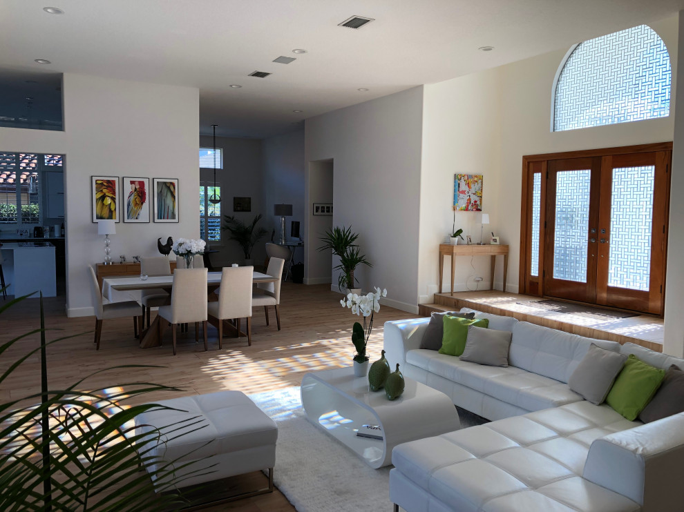 Mittelgroßes, Repräsentatives, Offenes Modernes Wohnzimmer mit beiger Wandfarbe, braunem Holzboden, Kamin, verputzter Kaminumrandung, TV-Wand und braunem Boden in Tampa