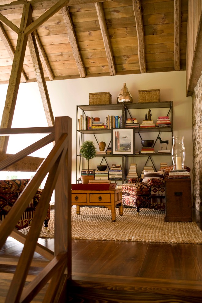 Esempio di un soggiorno country stile loft con libreria, pareti bianche e pavimento in legno massello medio